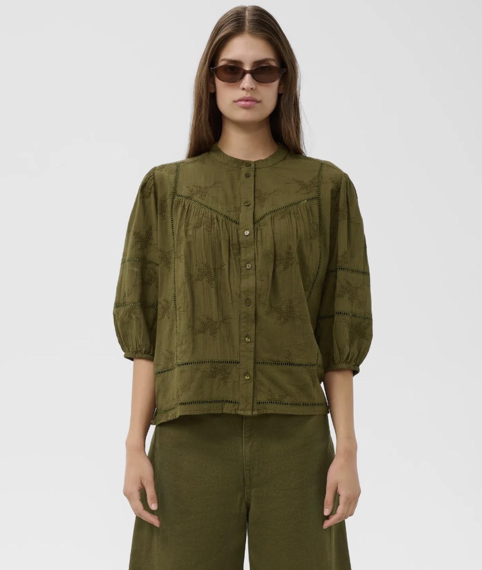 An olive green long-sleeve shirt with a subtle tonal floral pattern, shown on a model