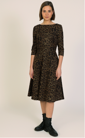 A woman modeling a brown and black leopard-print dress with three-quarter sleeves and a flared skirt, paired with black ankle boots, shown against a plain light background.