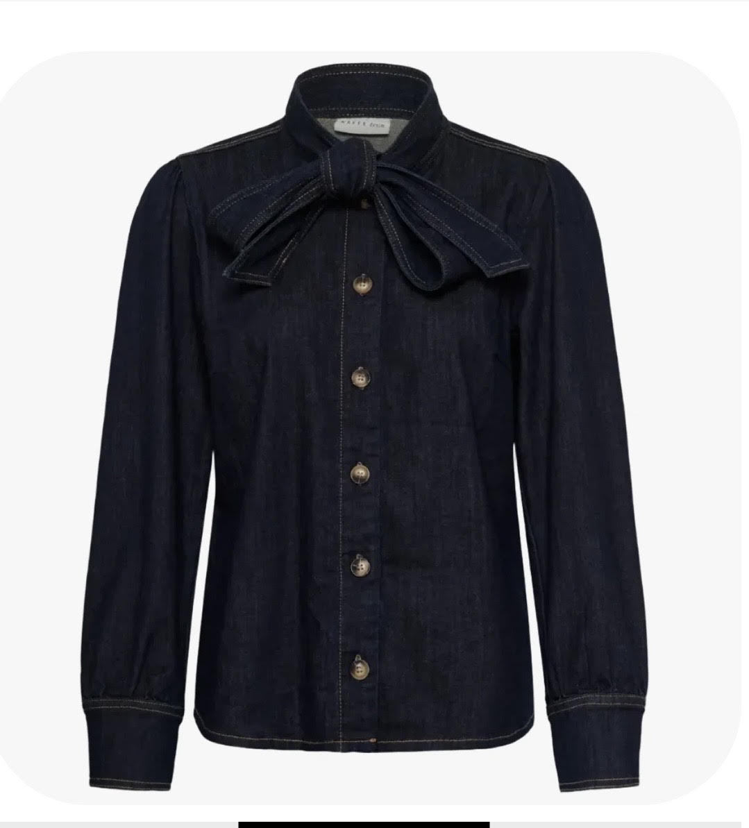 A dark indigo denim long-sleeve shirt jacket featuring a large bow detail at the collar and a button-down front, displayed on a light gray background.